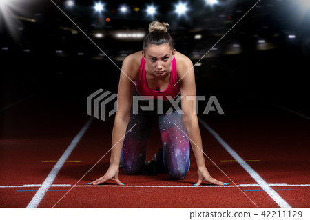 woman sprinter leaving starting blocks on the athletic track. exploding start on stadium with 42211129