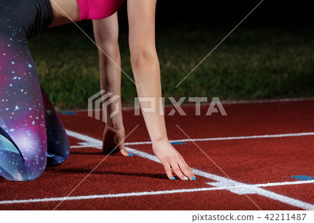 woman sprinter leaving starting blocks on the athletic track. exploding start on stadium with 42211487