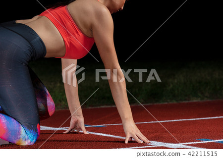 woman sprinter leaving starting blocks on the athletic track. exploding start on stadium with woman sprinter leaving starting blocks on the athletic track. exploding start on stadium with 42211515
