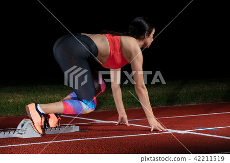 woman sprinter leaving starting blocks on the athletic track. exploding start on stadium with woman sprinter leaving starting blocks on the athletic track. exploding start on stadium with 42211519