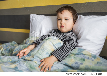 disappointed sick child boy sitting on bed 42213089