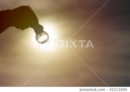 Silhouette hand holding light bulb with sunlight. 42213899