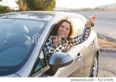 European woman behind the car wheel showing car key 42214306