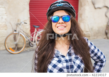 Young woman with sunglasses and helmet in street on sunny day Young woman with sunglasses and helmet in street on sunny day 42214317