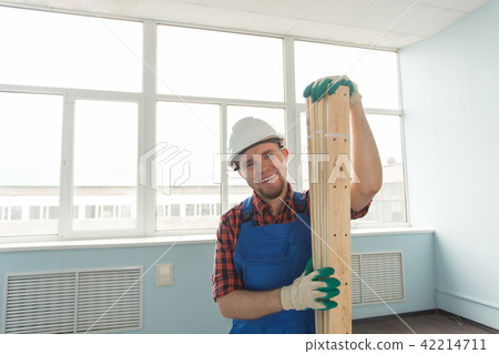 Closeup portrait of handsome male builder with wooden boards, wearing gloves. Closeup portrait of handsome male builder with wooden boards, wearing gloves. 42214711
