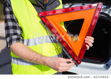A man holding a triangular sign of an accident 42214828