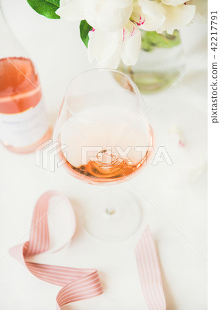 Rose wine in glass and bottle, pink ribbon, peony flowers Rose wine in glass and bottle, pink ribbon, peony flowers 42217791