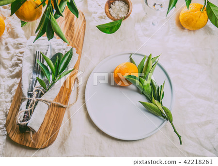 Table setting with white plate, cutlery, linen napkin and orange tree branch decoration on white Table setting with white plate, cutlery, linen napkin and orange tree branch decoration on white 42218261