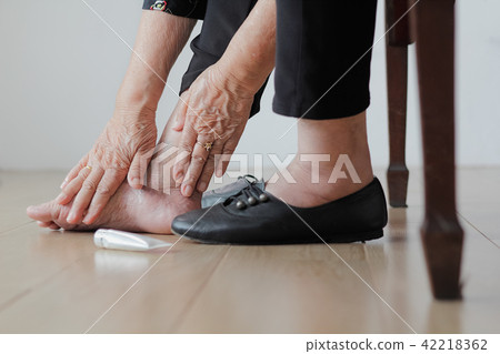 Elderly woman putting cream on swollen feet Elderly woman putting cream on swollen feet 42218362