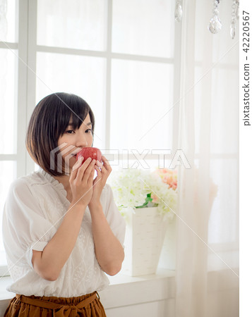 Girl eating fruit by the window Girl eating fruit by the window 42220567