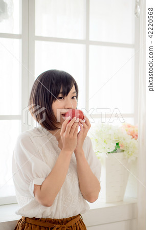 Girl eating fruit by the window Girl eating fruit by the window 42220568