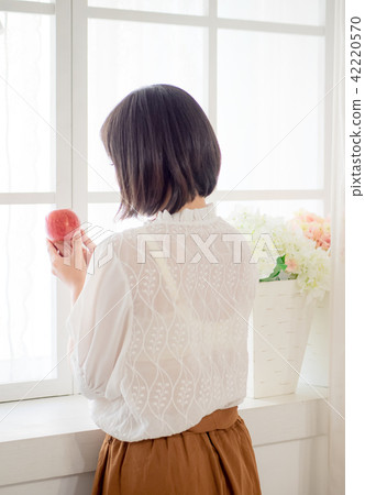 Girl eating fruit by the window Girl eating fruit by the window 42220570