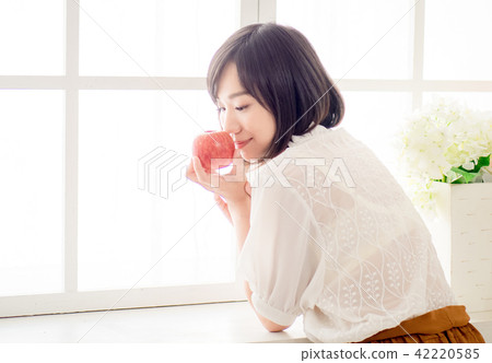 Girl eating fruit by the window 42220585