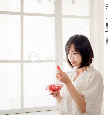 Girl eating fruit by the window Girl eating fruit by the window 42220613