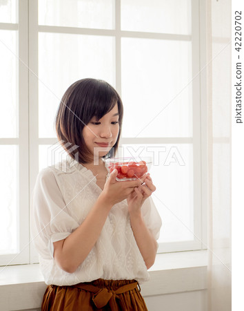 Girl eating fruit by the window Girl eating fruit by the window 42220702