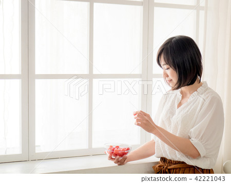 Girl eating fruit by the window 42221043