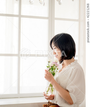Girl holding flowers by the window 42221268