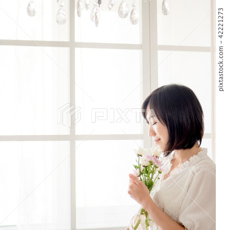 Girl holding flowers by the window Girl holding flowers by the window 42221273