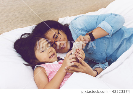 mom and her daughter are using a smartphone mom and her daughter are using a smartphone 42223374