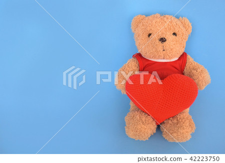 Teddy bear hold a heart shaped on blue background. Teddy bear hold a heart shaped on blue background. 42223750