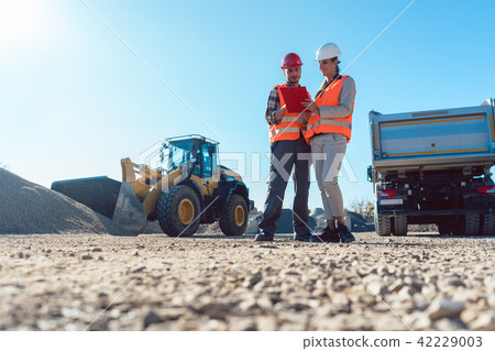 Worker and engineer on earthworks construction site planning Worker and engineer on earthworks construction site planning 42229003