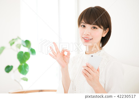 拿著智能手機和做一個好標誌的婦女 42230517