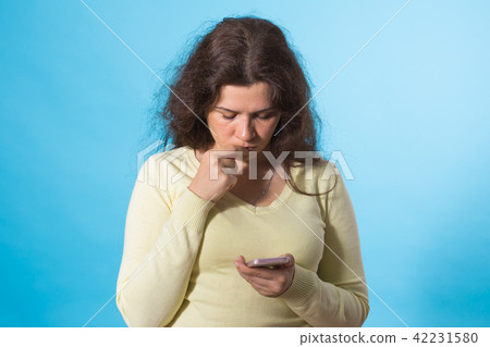 Beautiful Girl holding smart phone and send sms on blue Background Beautiful Girl holding smart phone and send sms on blue Background 42231580
