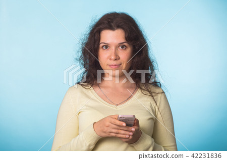 Young beautiful woman holding mobile phone studio on blue color background. 42231836