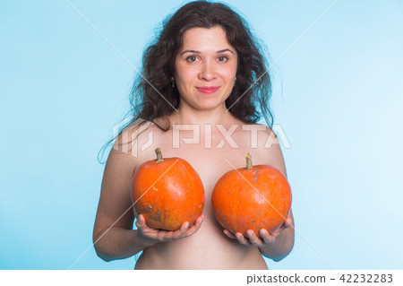 Pumpkins on a female breast - concept silicone breast and plastic surgery. Pumpkins on a female breast - concept silicone breast and plastic surgery. 42232283