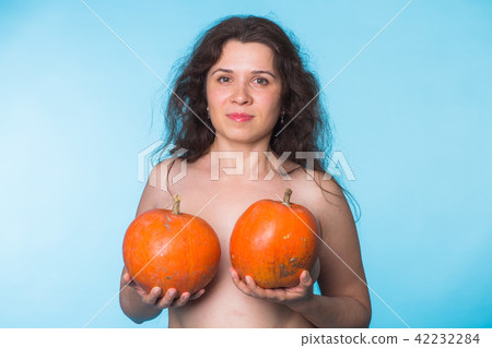 Breasts implant concept - Happy woman holding two pumpkins in front of her breasts Breasts implant concept - Happy woman holding two pumpkins in front of her breasts 42232284