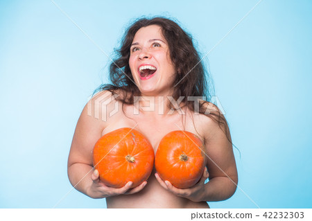 Pumpkins on a female breast - concept silicone breast and plastic surgery. Pumpkins on a female breast - concept silicone breast and plastic surgery. 42232303