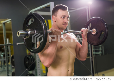 Handsome power athletic man with barbell. Strong bodybuilder with six pack, perfect abs, shoulders 42233269