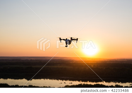 silhouette of drone, quadrocopter with photo camera flying in the sky. 42233486