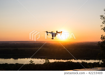 silhouette of drone, quadrocopter with photo camera flying in the sky. silhouette of drone, quadrocopter with photo camera flying in the sky. 42233489