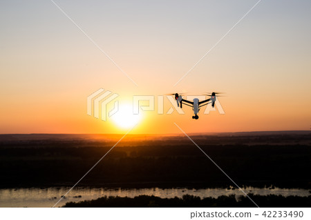 silhouette of drone, quadrocopter with photo camera flying in the sky. silhouette of drone, quadrocopter with photo camera flying in the sky. 42233490