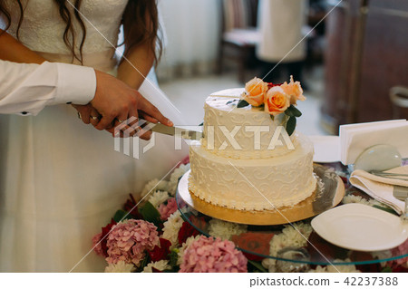 The hands of the newlywed couple cutting their first piece of the wedding cake. 42237388