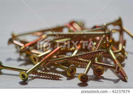 Pile of yellow screws on wooden background Pile of yellow screws on wooden background 42237674