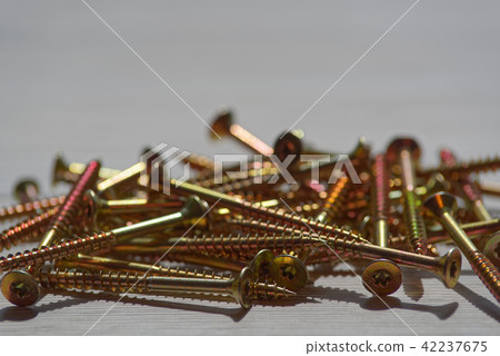 Yellow shiny screws scattered on wooden background Yellow shiny screws scattered on wooden background 42237675
