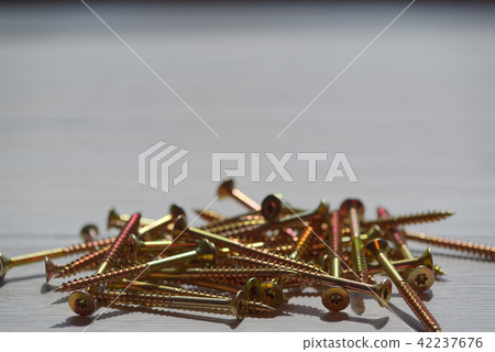 Yellow shiny screws scattered on wooden background Yellow shiny screws scattered on wooden background 42237676