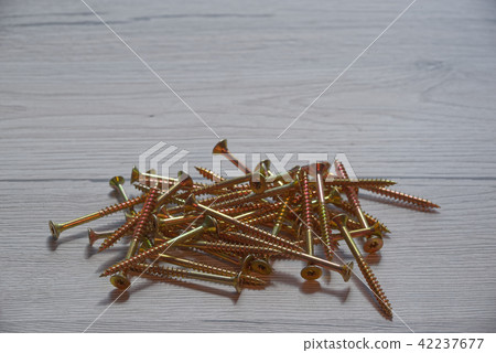 Pile of yellow screws on wooden background Pile of yellow screws on wooden background 42237677