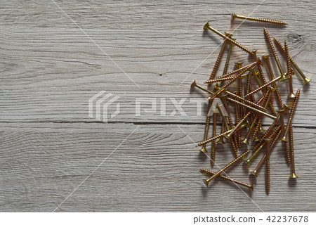 Yellow screws are laid out on wooden background Yellow screws are laid out on wooden background 42237678