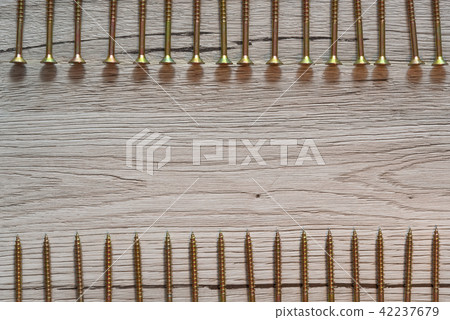 Yellow screws in two rows on wooden background Yellow screws in two rows on wooden background 42237679