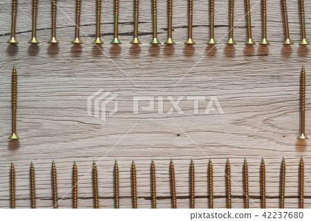 Yellow screws in two rows on wooden background Yellow screws in two rows on wooden background 42237680