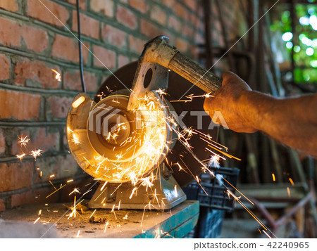 farmer sharpens a hack on electric grindstone 42240965