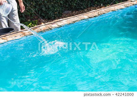 man pours of disinfectant in outdoor swimming pool 42241000