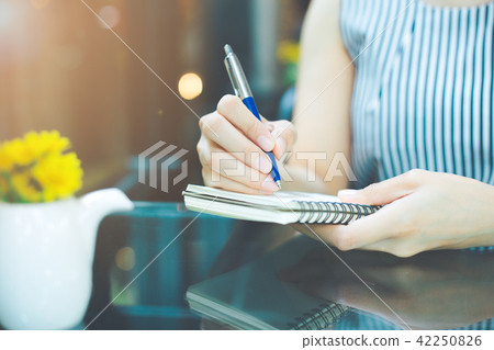 Business woman writing on a notebook with a pen. 42250826