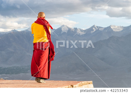 Indian tibetan monk standing in front of mountains 42253343