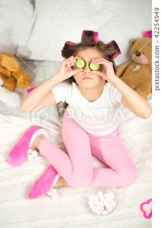 Little girl with cucumber slices on her eyes. 42254949