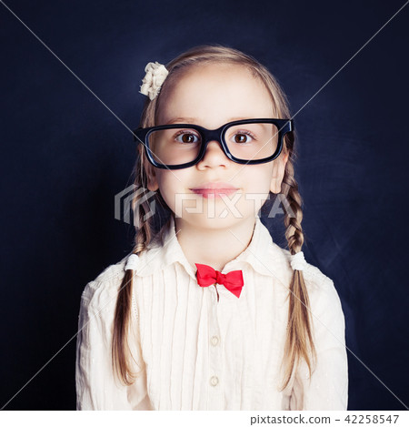 Smiling little girl in glasses on blue chalkboard Smiling little girl in glasses on blue chalkboard 42258547