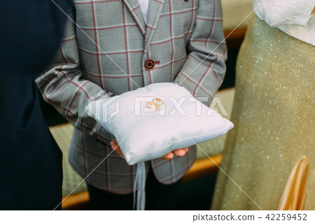 The blue silk pillow with the wedding rings on it. 42259452